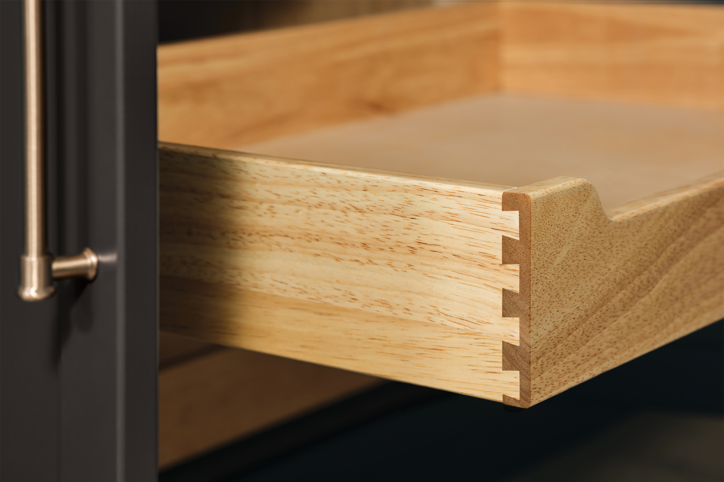 Detail of a KraftMaid Deluxe Roll-Out Tray showing dovetail joinery connecting solid-wood drawer box sides